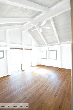 an empty room with wood floors and white walls