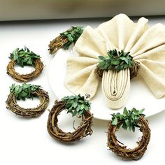 a white plate topped with green wreaths and napkin rings on top of a table