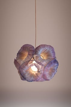 a purple lamp hanging from a ceiling with two lights on it's sides and one light in the middle