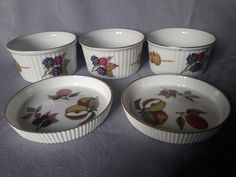 four bowls with fruit designs on them sitting next to each other in front of a gray background