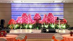 the stage is decorated with bright pink and orange decorations, along with white clothed tables