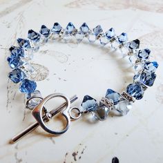 Elegant light blue sapphire and denim blue crystal bracelet is a great gift for women who love exquisite and sparkly blue jewelry. Handmade with Swarovski crystals and Swarovski rhinestone crowns and finished with a sterling silver toggle clasp.  A great gift for a mother of the bride or groom's mom. Luxe and gorgeous sapphire anniversary gift for your wife. A thoughtful gift for a woman born in September since blue sapphire is her birthstone. Bracelet Details: - Bracelet is .5 inches wide (1.27 Adjustable Blue Crystal Bracelet For Anniversary, Elegant Blue Faceted Crystal Bracelet, Adjustable Blue Bracelets With Sparkling Stones, Blue Faceted Crystal Bracelets, Blue Crystal Bracelet With Sparkling Stones, Blue Faceted Crystal Bracelet For Gifts, Blue Faceted Crystal Bracelet Gift, Blue Crystal Bracelets For Anniversary, Handmade Blue Crystal Bracelet