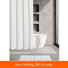 a white bathtub sitting next to a shower curtain in a bathroom with the words now trending, $ 50 & under