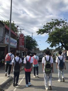 several people walking down the street with backpacks on