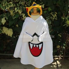 a white cape with red and yellow teeth on it's head, attached to a wooden stand