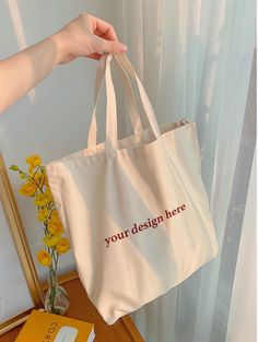 a person holding a white bag with the words, your design here printed on it