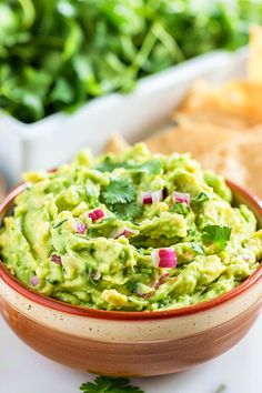 a bowl filled with guacamole next to tortilla chips