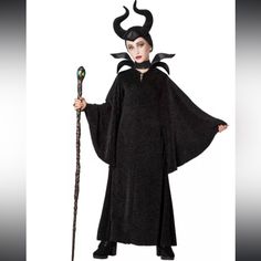 a woman dressed as maleficent holding a wand and wearing a black costume with horns