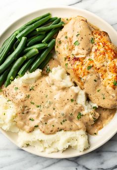 chicken with gravy, mashed potatoes and green beans on a plate