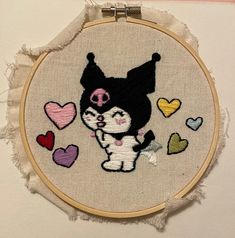 a cat and dog cross stitched together on a piece of fabric with hearts in the background