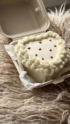 a heart shaped cake in a box on a furry surface