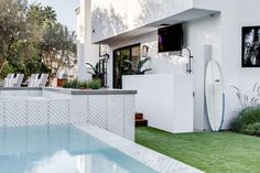 a surfboard is leaning against the wall next to a swimming pool in front of a house