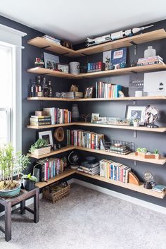 a bookshelf filled with lots of books in a living room next to a window