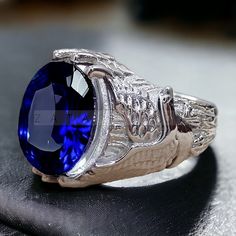 a ring with a large blue stone in the center on a black cloth surface,