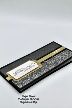 a black and gold business card with a name tag attached to it's side