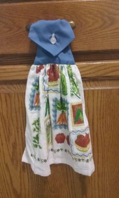 a blue and white dress hanging on a wooden door handle in front of a brown cabinet