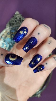 a woman's hand with blue and gold nail polishes on her nails, holding a