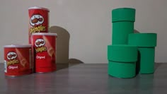 three cans of peanut butter sitting on top of a table next to stacks of green cups