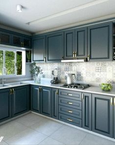 a kitchen with blue cabinets and white counter tops, along with potted plants on the window sill