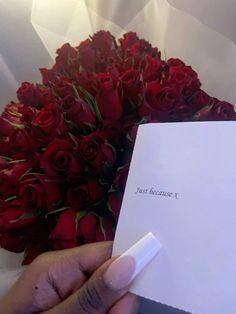 someone holding a bouquet of red roses in front of a white card that says just because i love you