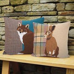 three decorative pillows on a bench in front of a brick wall