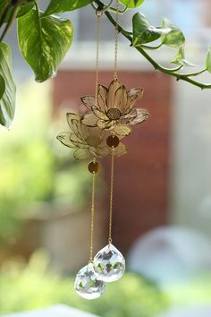 a glass sun catcher hanging from a tree branch with two crystal beads attached to it