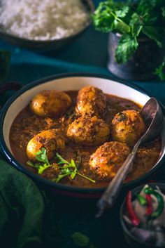 a bowl filled with meatballs and sauce next to other food on a table top