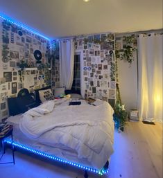 an unmade bed in a room with blue lights on the wall and pictures all over the walls