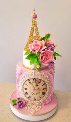 a pink cake with flowers and a clock on the top is decorated like a tower