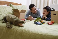 a man and child laying on a bed with toys