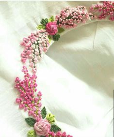 a white shirt with pink flowers and green leaves on the front, along with an embroidered collar