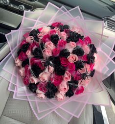 a bouquet of pink and black roses in a car