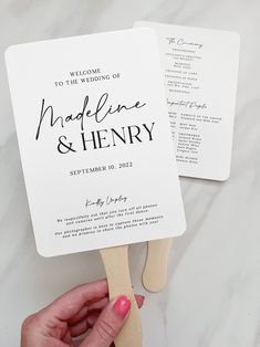 a person holding two fan shaped fans with the names of their wedding and date printed on them