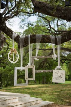 an outdoor wedding ceremony is hanging from a tree with ribbons and tags attached to it