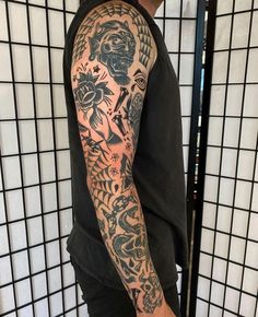 a man with a tattoo on his arm is standing in front of a tiled wall