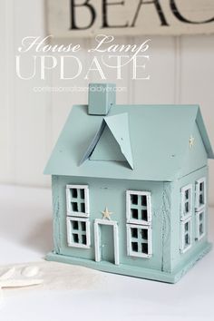 a small blue house sitting on top of a white table next to a beach sign