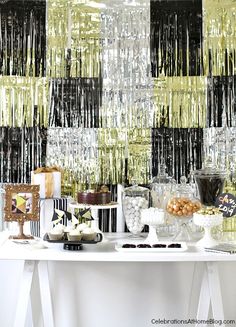 a table topped with cakes and desserts next to a wall covered in sequins