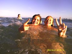 two women in the water making peace signs