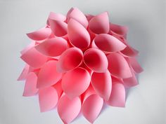 a large pink paper flower on a white background with room for text or image to be added