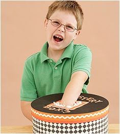 a young boy sitting at a table with a cake in front of him and his mouth open