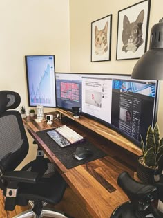 two computer monitors sitting on top of a wooden desk