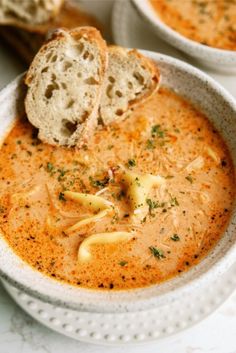 there is a bowl of soup with bread on the side