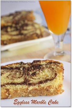 an eggless marble cake on a white plate next to a glass of orange juice