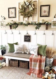 a bench with pillows and blankets on it in front of a wall filled with pumpkins