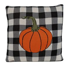 a black and white checkered pillow with an orange pumpkin embroidered on the front side