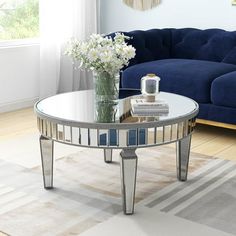 a living room with a blue couch and white flowers in a vase on the coffee table