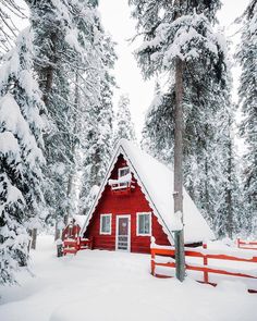 a small red cabin in the woods covered in snow