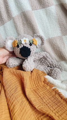 a hand holding a stuffed animal on top of a bed