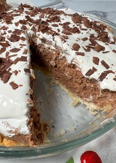 a chocolate cake with white frosting on a glass platter next to an apple