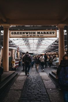 people are walking under the greenway market sign